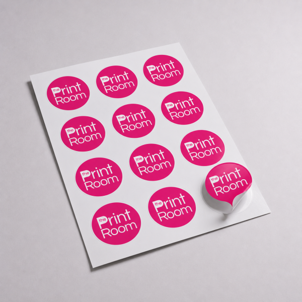 Print Room branded circular stickers on a gloss white self-adhesive sheet, with one kiss-cut sticker partially peeled on a light grey studio background.