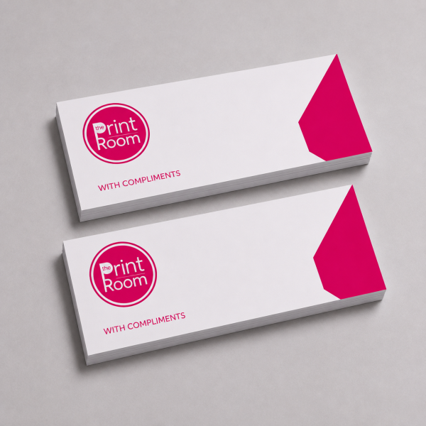 Custom compliment slips featuring the Print Room circular logo and pink geometric corner accent, displayed as two stacked pads on a light grey studio background.