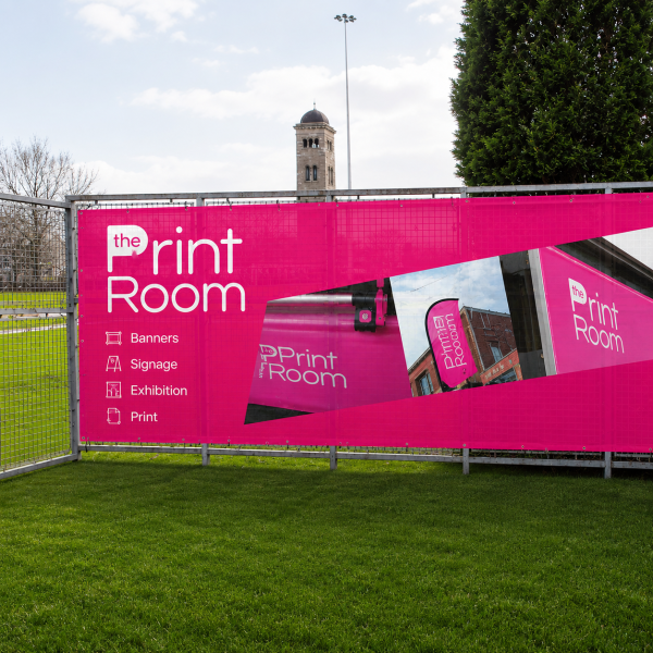 Custom printed mesh banner installed on a metal fence featuring The Print Room branding, demonstrating a vibrant outdoor advertising display with wind-permeable mesh material.