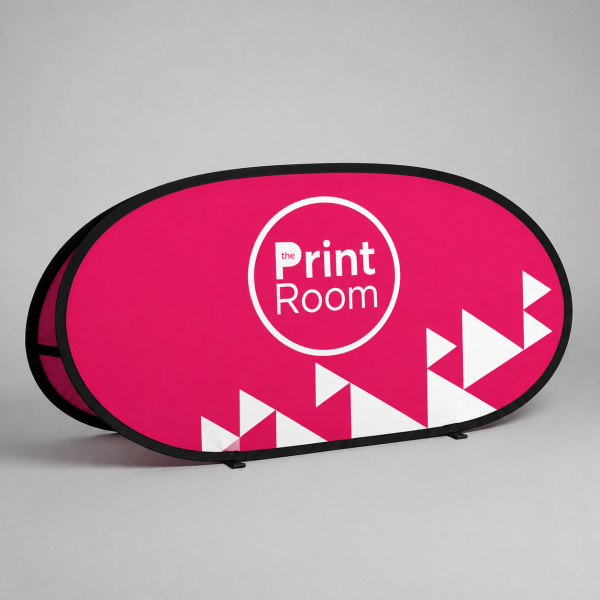 Oval pop up banner featuring the white circular Print Room logo on a vibrant pink background, displayed in a studio setting for indoor and outdoor promotional branding.
