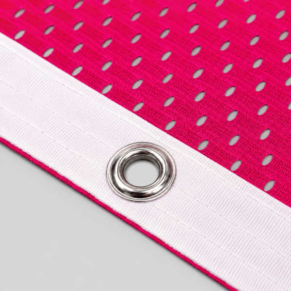 The Print Room AirMesh Scrim Banner featuring pink perforated mesh, reinforced white hem, and metal eyelets, designed for durable outdoor branding and event displays.